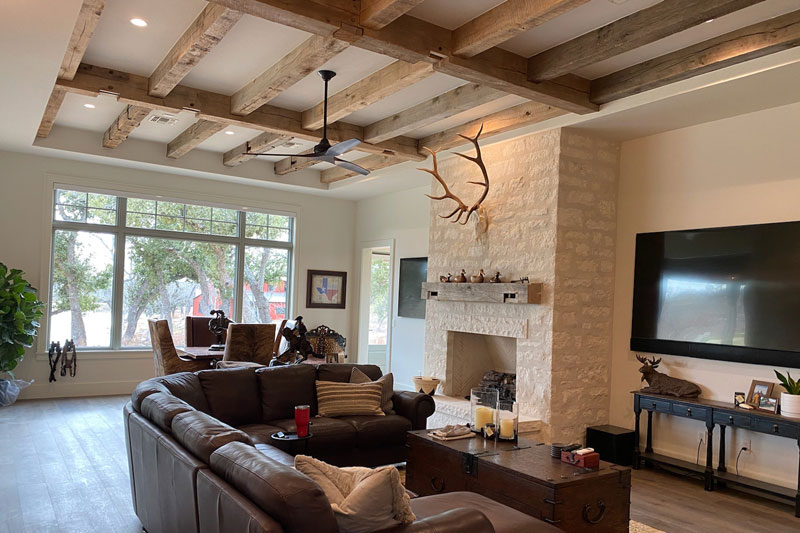 Sawn barn timber beams over a living room with a stone fireplace